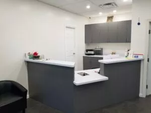 View of receptionist area with modern gray cabinets and white top counter at Crystal Bright Smile Dental Office in Tujunga, CA.