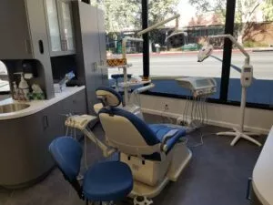 A close-up view of a dental work chair at Crystal Bright Smile Dental Office in Tujunga, CA. The space is clean and well-lit, with a modern blue and white color motif. The chair faces the window for a beautiful street view.