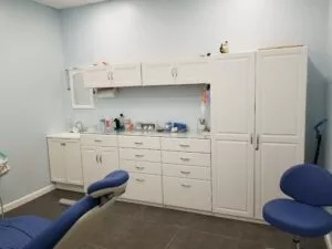 A close-up view of a dental work chair and cabinets in an enclosed dental office at Crystal Bright Smile Dental Office in Tujunga, CA. The space is clean and well-lit, with a modern blue and white color motif.