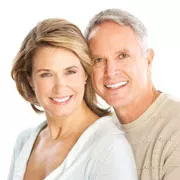 Caucasian woman and man in their 40s smiling in a portrait pose, displaying a bright smile from full and partial dentures received at Crystal Bright Smile in Tujunga, California.